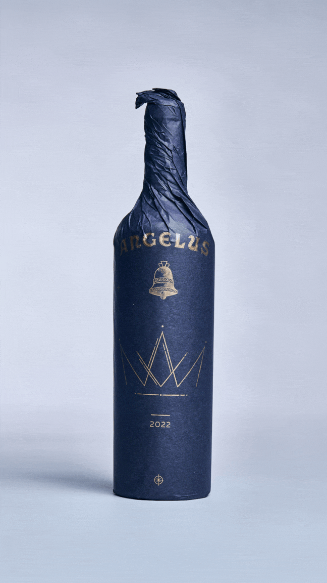 Packaging complet du millésime 2022 de Château Angelus, papier bleu nuit constellé d'or, coffret en bois gravé et livret Le Majestueux