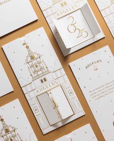 Carte de vœux Château Angelus en papier blanc grainé avec marquage à chaud doré représentant la façade du château, coffret miniature gravé du millésime 2025